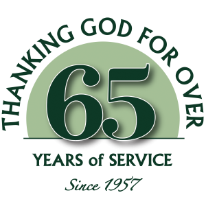 A graphic reads “Thanking God for over 65 years of service. Since 1957” in green text with a large “65” centered inside a green semicircle.