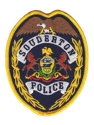 A gold-trimmed police badge featuring an eagle, two horses, a shield, and the text "Souderton Police" in bold letters.
