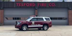 A Telford Fire Rescue SUV is parked in front of the Telford Fire Co. building with three large garage doors and red lettering on the facade.