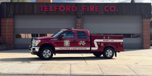 A red Telford Fire Rescue truck is parked in front of a fire station with "Telford Fire Co." in large red letters above three closed garage doors.