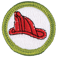 An embroidered patch with a green border featuring a red firefighter helmet on a white background—perfect for recognizing a Community Spotlight: A Young Scout Making a Big Impact on Fire Safety.