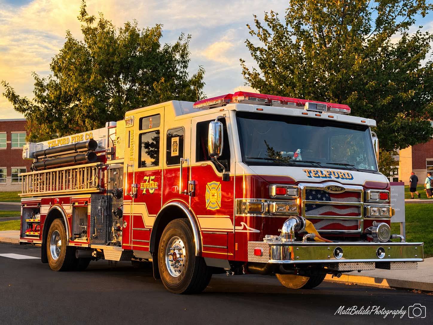 A red and white Telford Fire Company engine parked on an asphalt street with trees in the background.